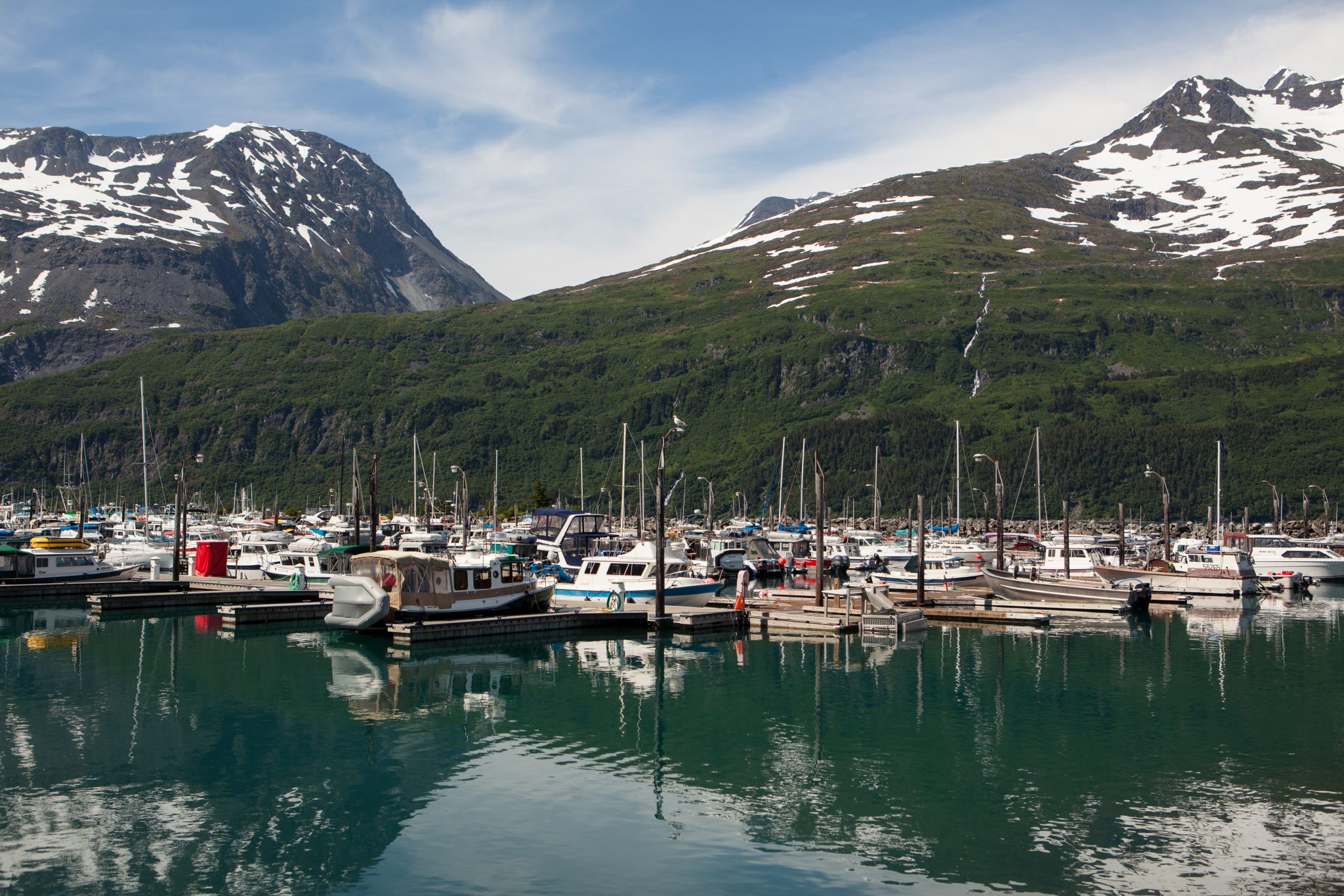 boats anchored in Whittier Harbor underneath two mountains that still hold scattered snow