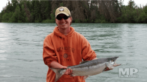 Fishermen in orange hoodie hat holds a fish