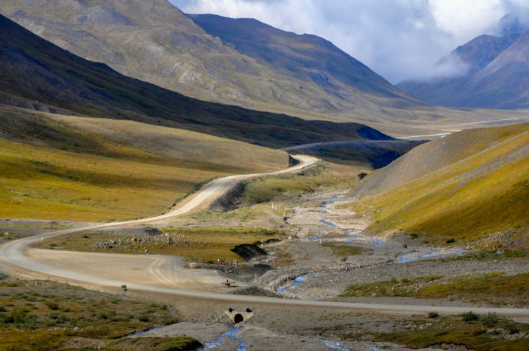 The gravel dalton highway winds through a narrow valley, Atigun Valley