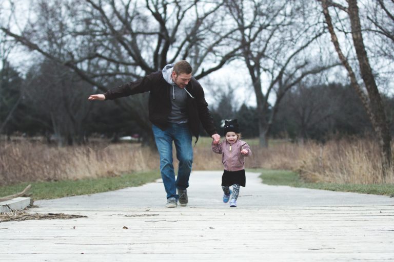 Dad and daughter hold hands and run while smiling