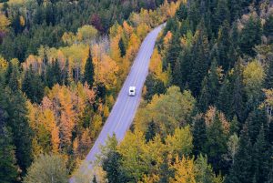 A motorhome driving on a two-lane road through fall colors