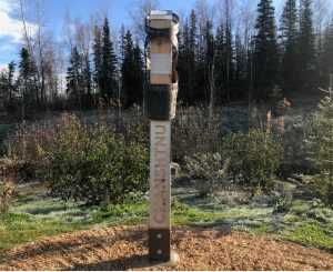 A wooden sign with metal plaque that reads Chanshtnu, one of the indigenous Dena'ina names being recognized around Anchorage