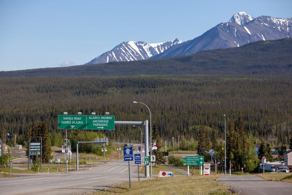 Road leads to big signs pointing to Alaska Highway for a right turn and straight for Haines Road to Haines, Alaska