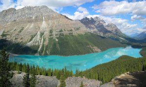 A long, narrow turquoise lake at the base of steep, rocky mountains