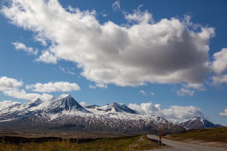 Bicycle the Golden Circle Loop Empty highway curves along the bottom of the photo and mountains still capped with snow dominate the landscape ahead